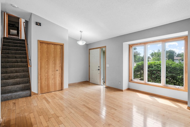 3649 Tower Pond Dr, Anoka, MN 55303 - unfurnished living room with lofted ceiling, light wood finished floors, stairway, and a textured ceiling