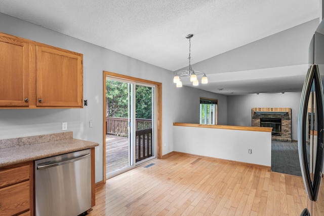 3649 Tower Pond Dr, Anoka, MN 55303 - kitchen featuring dishwasher, lofted ceiling, light wood-style floors, a chandelier, and a brick fireplace