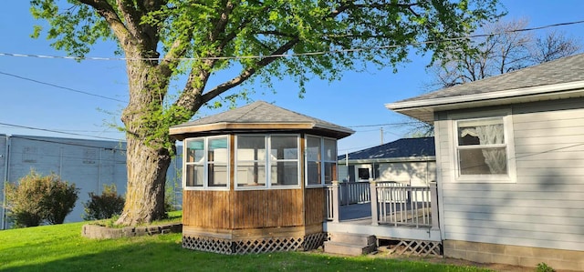 621 16th St, Albert Lea, MN 56007 - rear view of house featuring a wooden deck, roof with shingles, a yard, and a sunroom