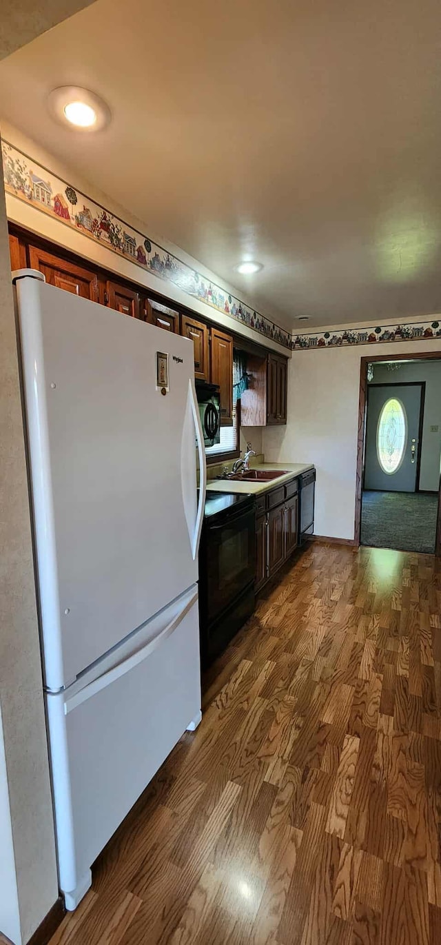 621 16th St, Albert Lea, MN 56007 - kitchen featuring freestanding refrigerator, black range with electric cooktop, dark wood-type flooring, dark brown cabinetry, and a sink