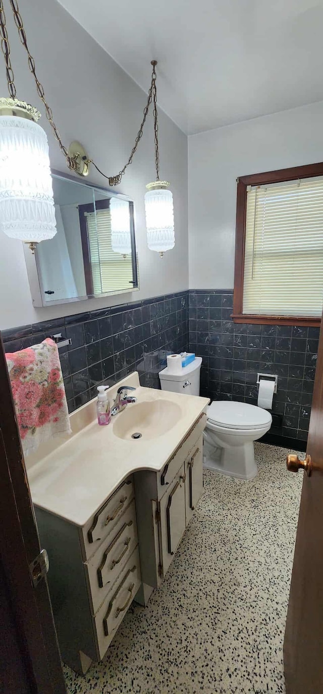 621 16th St, Albert Lea, MN 56007 - bathroom with tile walls, toilet, vanity, wainscoting, and speckled floor