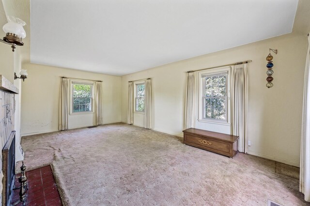 unfurnished living room with carpet, a brick fireplace, and baseboards
