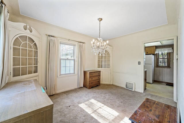 unfurnished dining area with carpet flooring, a chandelier, and baseboards