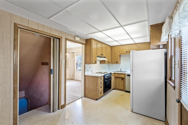 kitchen with freestanding refrigerator, electric range oven, under cabinet range hood, a sink, and light countertops