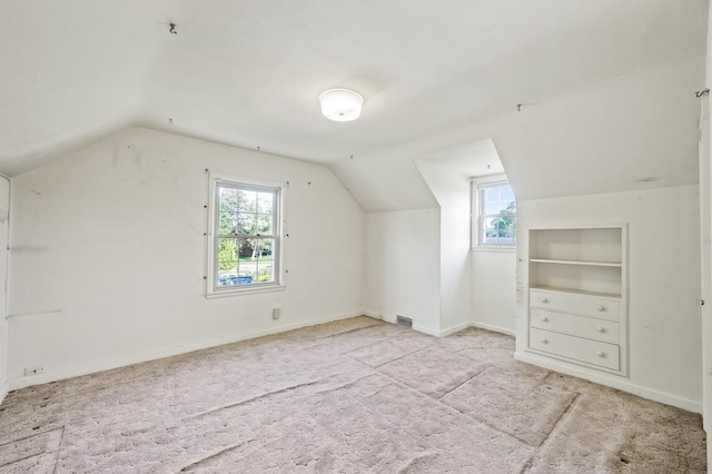 additional living space with lofted ceiling, healthy amount of natural light, carpet, baseboards, and built in features