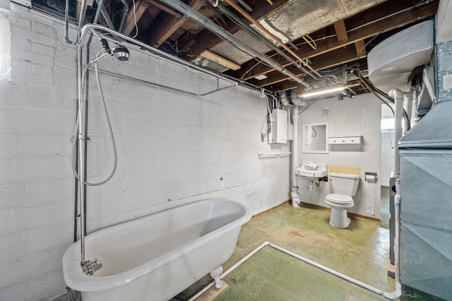 full bathroom featuring a freestanding tub, electric panel, a sink, toilet, and concrete floors