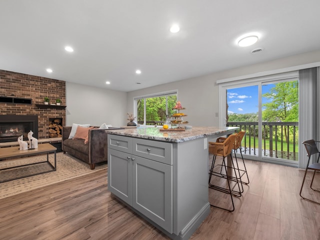 2908 Crestwood Dr NE, Alexandria Twp, MN 56308 - kitchen with gray cabinetry, light wood-style flooring, a breakfast bar, light stone counters, and recessed lighting