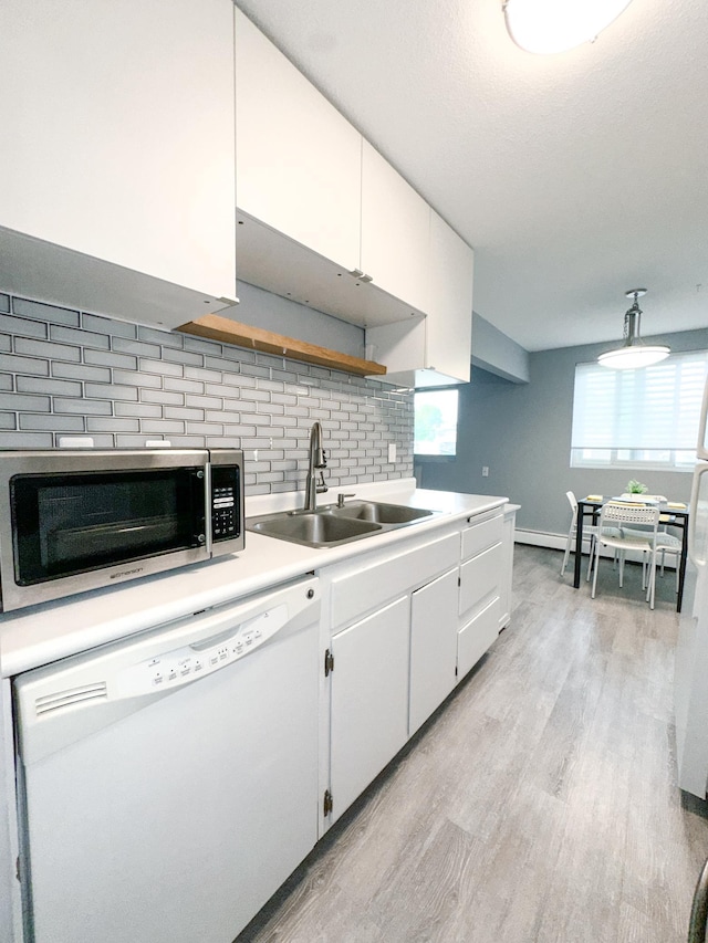 4407 Wilshire Blvd Unit 110, Mound, MN 55364 - kitchen with dishwasher, a sink, stainless steel microwave, light wood finished floors, and white cabinetry