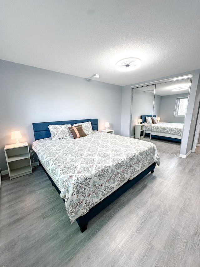 4407 Wilshire Blvd Unit 110, Mound, MN 55364 - bedroom with wood finished floors, a closet, a textured ceiling, and baseboards