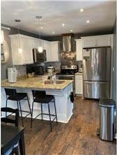 3422 Highlander Dr, Eagan, MN 55122 - kitchen with stainless steel appliances, white cabinets, light countertops, and wall chimney range hood
