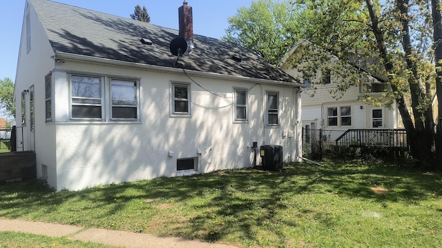 1339 Payne Ave, Saint Paul, MN 55101 - rear view of house with a yard, cooling unit, a chimney, a shingled roof, and stucco siding