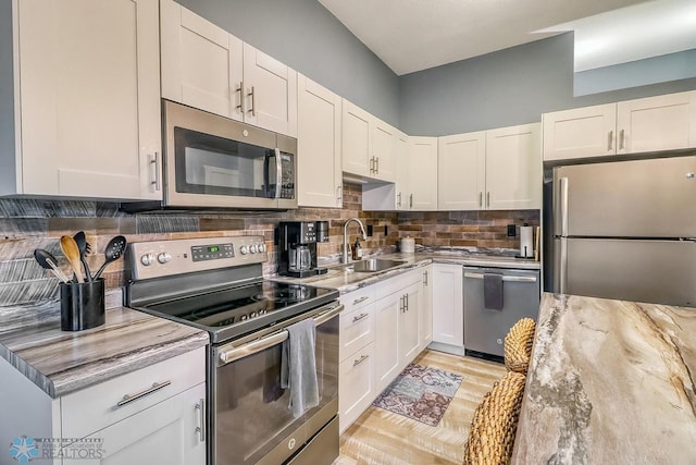 2814 26th Street Cir S, Moorhead, MN 56560 - kitchen with appliances with stainless steel finishes, light stone counters, white cabinets, decorative backsplash, and a sink
