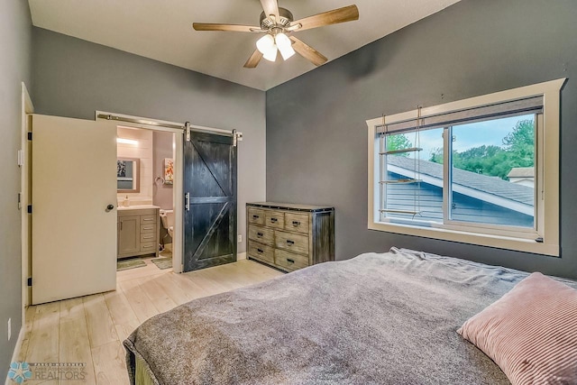 2814 26th Street Cir S, Moorhead, MN 56560 - bedroom featuring a barn door, light wood-style floors, connected bathroom, and ceiling fan