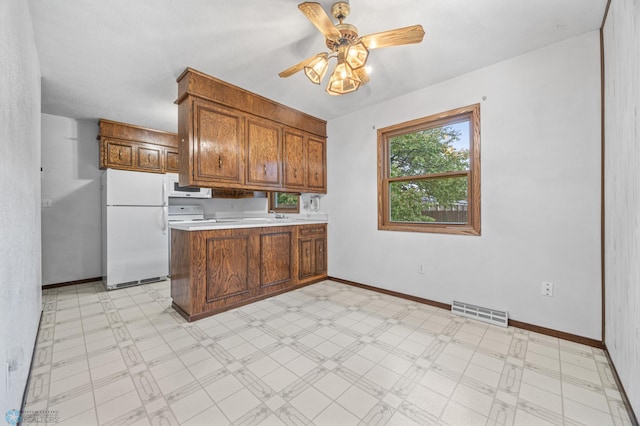 2207 16th St S, Fargo, ND 58103 - kitchen featuring white appliances, a peninsula, brown cabinetry, ceiling fan, and light countertops