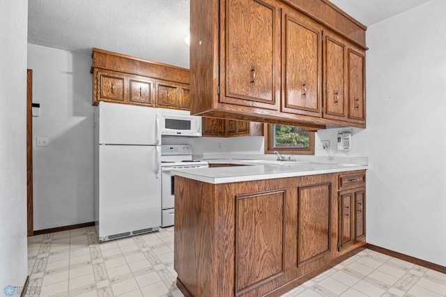 2207 16th St S, Fargo, ND 58103 - kitchen featuring white appliances, brown cabinets, a peninsula, light flooring, and a textured ceiling