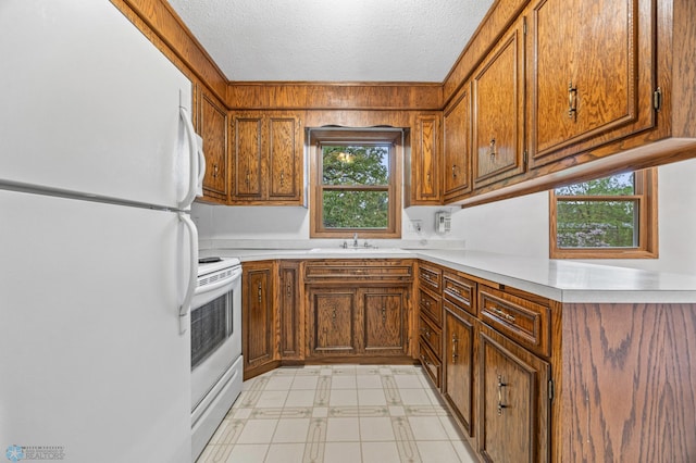 2207 16th St S, Fargo, ND 58103 - kitchen with white appliances, brown cabinets, light countertops, a textured ceiling, and a sink