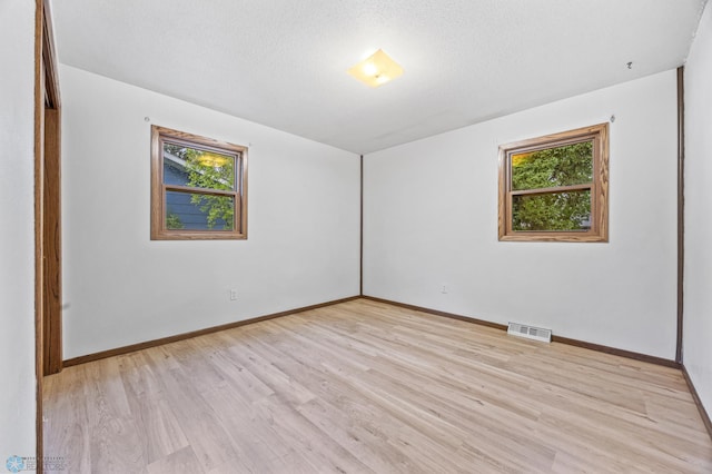 2207 16th St S, Fargo, ND 58103 - empty room featuring plenty of natural light, light wood finished floors, baseboards, and a textured ceiling