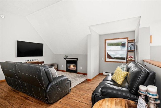25 Maki Rd, Esko, MN 55733 - living area with baseboard heating, wood finished floors, vaulted ceiling, baseboards, and a glass covered fireplace