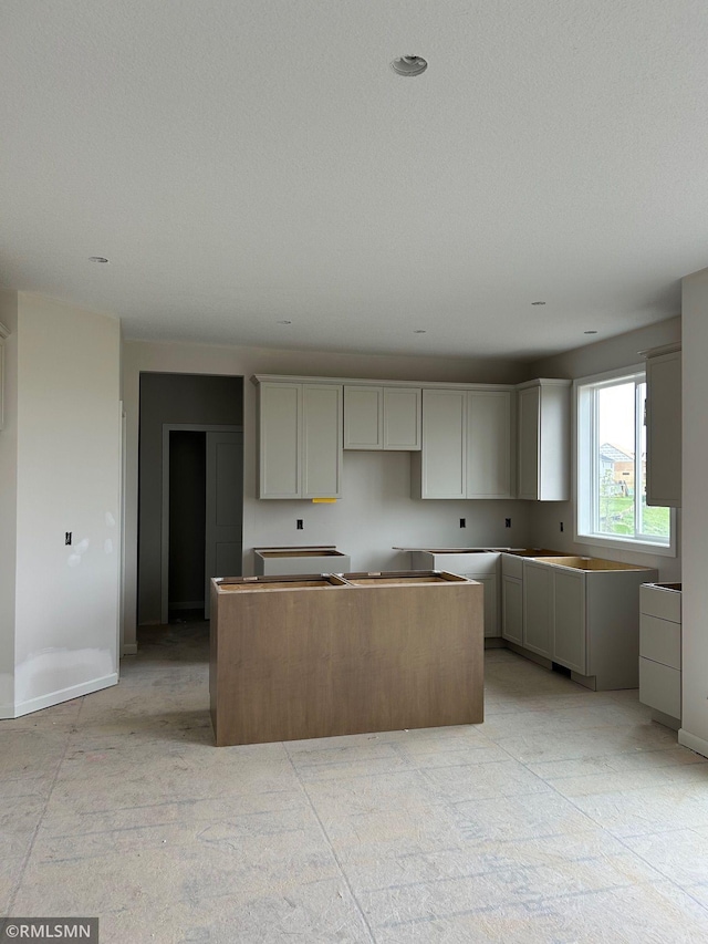 10101 Blackmoor Rd, Woodbury, MN 55129 - kitchen with a center island, baseboards, and gray cabinetry