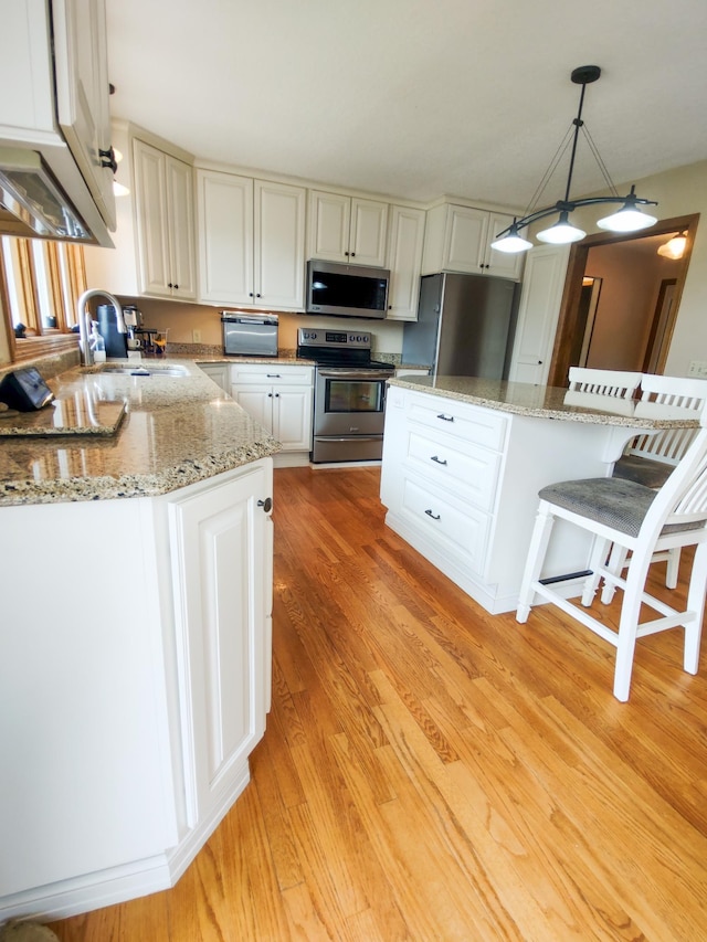 620 Maple St, Dassel, MN 55325 - kitchen featuring appliances with stainless steel finishes, a sink, light wood-style flooring, hanging light fixtures, and white cabinetry