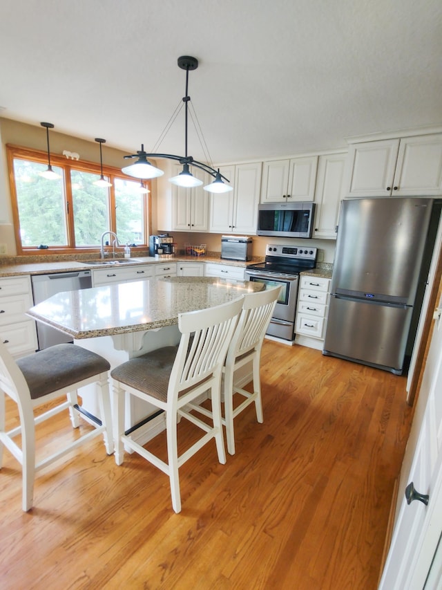 620 Maple St, Dassel, MN 55325 - kitchen with appliances with stainless steel finishes, white cabinets, pendant lighting, and a center island