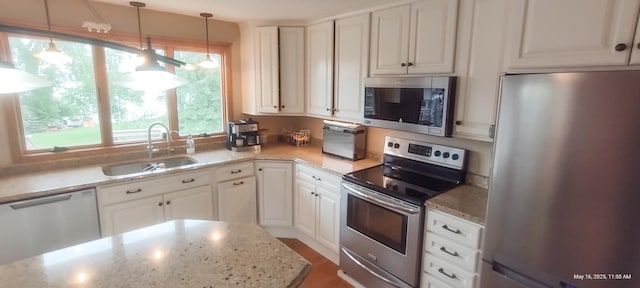 620 Maple St, Dassel, MN 55325 - kitchen featuring appliances with stainless steel finishes, a sink, light stone countertops, white cabinetry, and decorative light fixtures