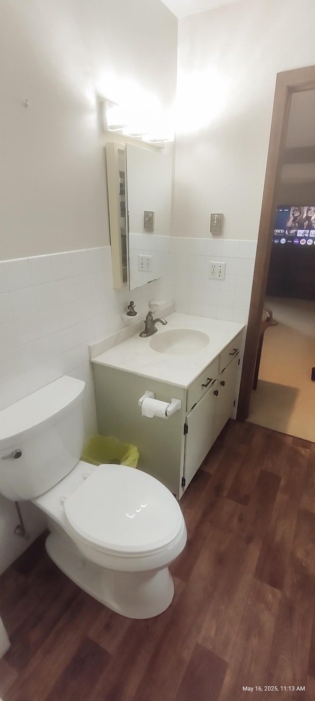 620 Maple St, Dassel, MN 55325 - half bath with tile walls, toilet, vanity, wood finished floors, and wainscoting