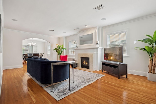 1785 Dupont Ave S, Minneapolis, MN 55403 - living room featuring ornamental molding, arched walkways, light wood-style floors, baseboards, and a chandelier