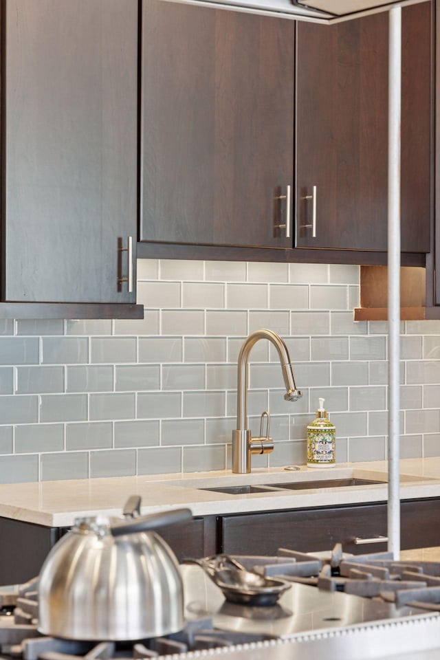1785 Dupont Ave S, Minneapolis, MN 55403 - kitchen view of dark brown cabinets, a sink, decorative backsplash, and light stone countertops