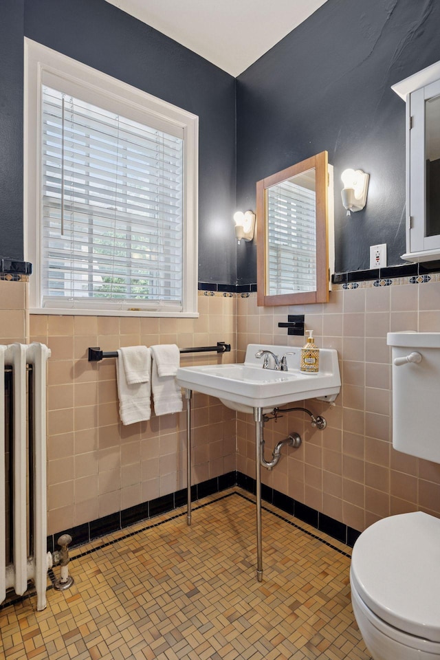 1785 Dupont Ave S, Minneapolis, MN 55403 - half bathroom featuring radiator, tile walls, toilet, a wainscoted wall, and a sink