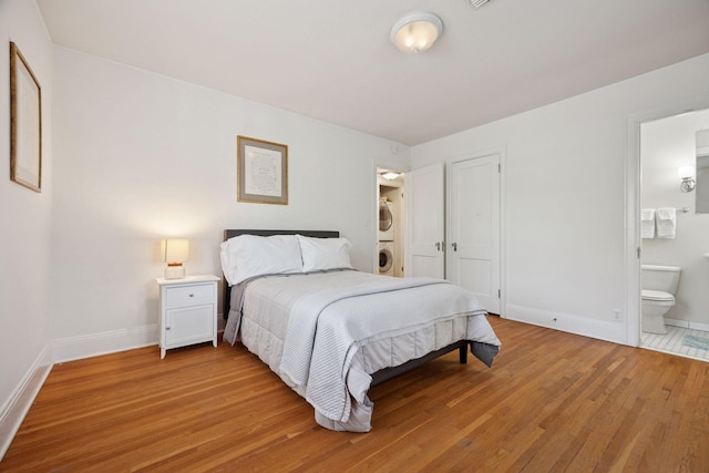 1785 Dupont Ave S, Minneapolis, MN 55403 - bedroom with stacked washer and clothes dryer, baseboards, light wood-style floors, and connected bathroom