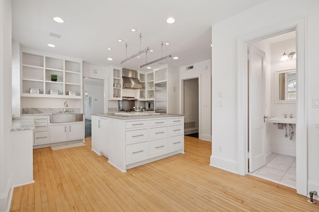 1785 Dupont Ave S, Minneapolis, MN 55403 - kitchen featuring open shelves, wall chimney range hood, white cabinets, a sink, and recessed lighting