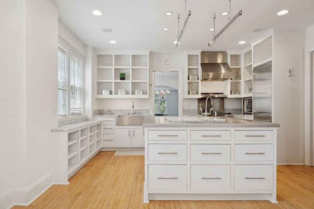 1785 Dupont Ave S, Minneapolis, MN 55403 - kitchen with open shelves, a sink, wall chimney exhaust hood, white cabinets, and built in fridge