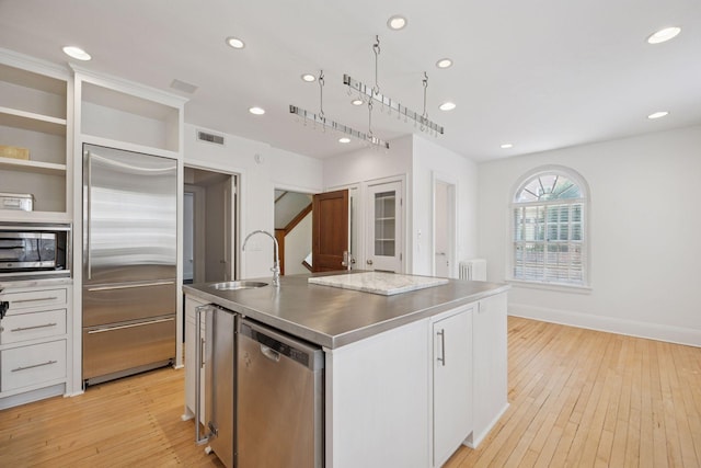 1785 Dupont Ave S, Minneapolis, MN 55403 - kitchen with stainless steel countertops, stainless steel appliances, a sink, light wood finished floors, and recessed lighting