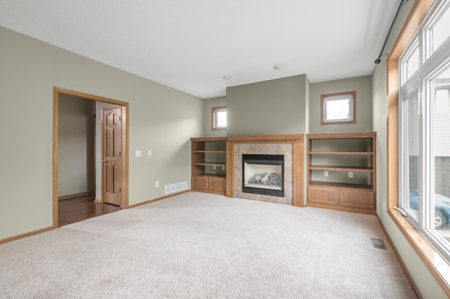 10543 Noble Cir N, Brooklyn Park, MN 55443 - unfurnished living room featuring carpet flooring, baseboards, a tiled fireplace, and plenty of natural light