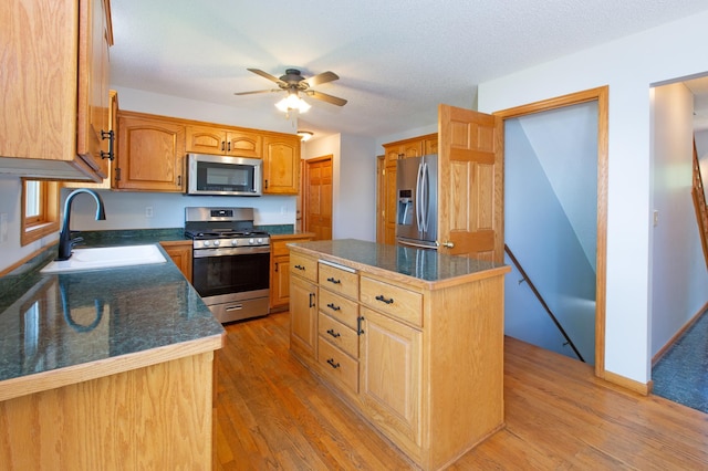 761 Country Lakes Dr, Lino Lakes, MN 55014 - kitchen with appliances with stainless steel finishes, a sink, light wood-style flooring, a ceiling fan, and a kitchen island