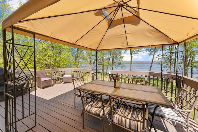 deck with a water view and outdoor dining space