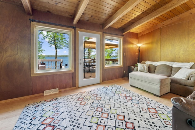 living area with beam ceiling, healthy amount of natural light, wood ceiling, wood finished floors, and wood walls