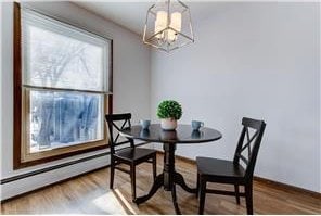 709 11th Ave S Unit 5, Hopkins, MN 55343 - dining space featuring a chandelier, wood finished floors, baseboards, and baseboard heating