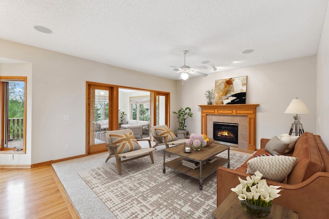3613 Clare Downs Path, Rosemount, MN 55068 - living area featuring light wood-style floors, a tile fireplace, a ceiling fan, baseboards, and a textured ceiling