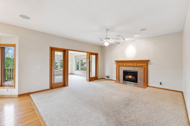 3613 Clare Downs Path, Rosemount, MN 55068 - unfurnished living room featuring a tiled fireplace, baseboards, a ceiling fan, a textured ceiling, and light wood-style floors