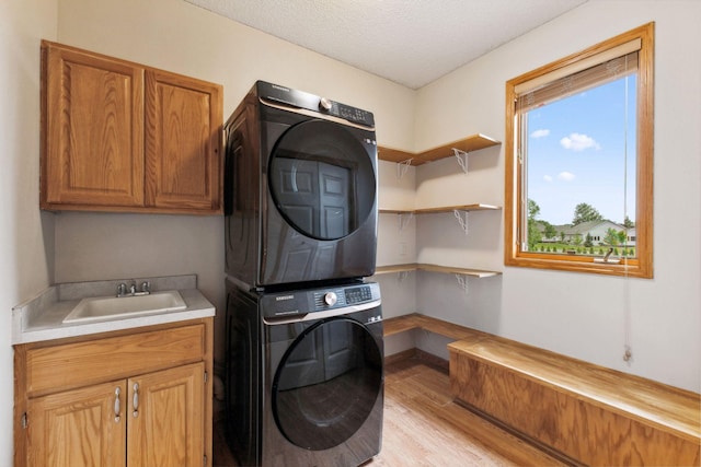 3613 Clare Downs Path, Rosemount, MN 55068 - laundry room with stacked washer and clothes dryer, cabinet space, light wood-style floors, a textured ceiling, and baseboards