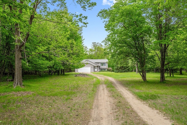 view of front of home featuring dirt driveway, a front lawn, and an attached garage