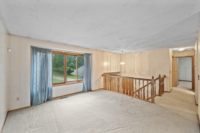 spare room with carpet, a textured ceiling, and baseboards