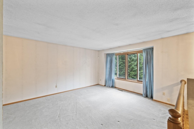 unfurnished room with a textured ceiling, carpet, and baseboards