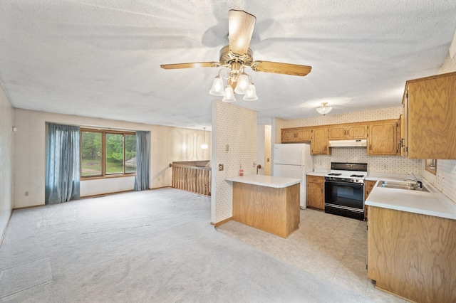kitchen featuring range with gas cooktop, freestanding refrigerator, light countertops, a peninsula, and under cabinet range hood