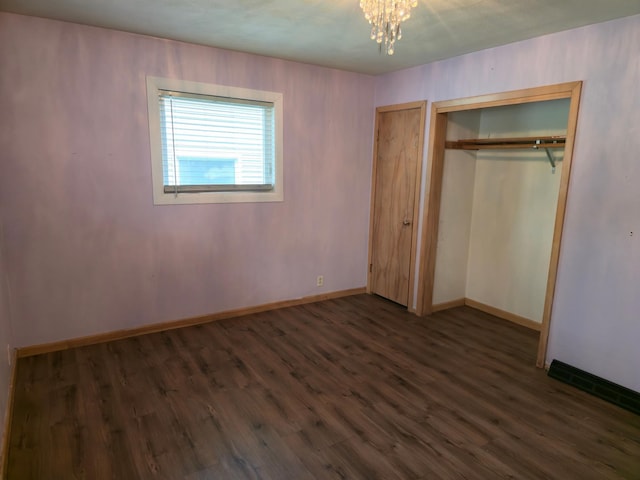 214 Central Ave, Truman, MN 56088 - unfurnished bedroom with dark wood-type flooring, a chandelier, baseboards, and a closet