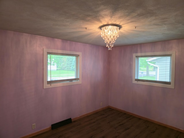 214 Central Ave, Truman, MN 56088 - unfurnished room with healthy amount of natural light, a chandelier, wood finished floors, and baseboards