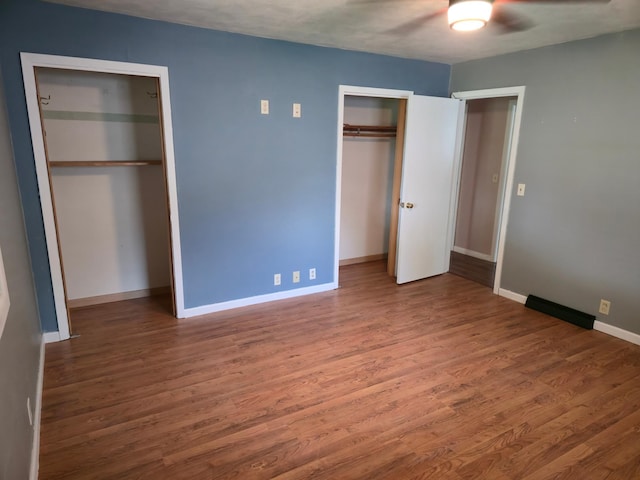 214 Central Ave, Truman, MN 56088 - unfurnished bedroom with multiple closets, wood finished floors, baseboards, and ceiling fan