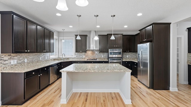 15365 Eagle Creek Way, Apple Valley, MN 55124 - kitchen with appliances with stainless steel finishes, wall chimney exhaust hood, a sink, a center island, and light wood-style flooring